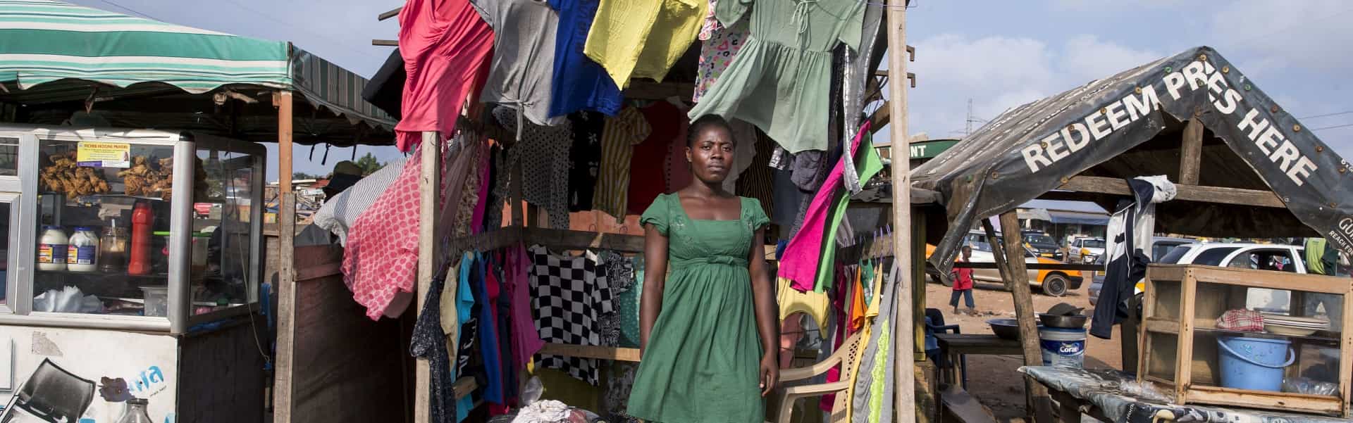 Ghanaian woman standing in clothing stall in wind