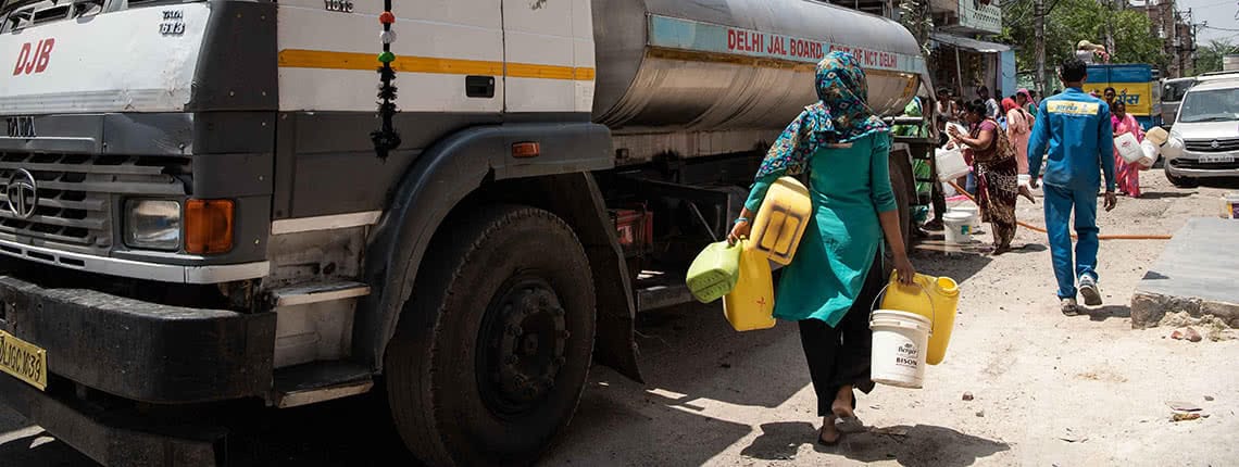 Woman getting water from distribution truck in Delhi, India