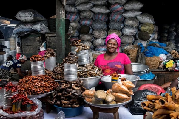 Monica Agyei in Accra stands in front of her array of foods for sale | Jonathan Torgovnik Getty Images Reportage