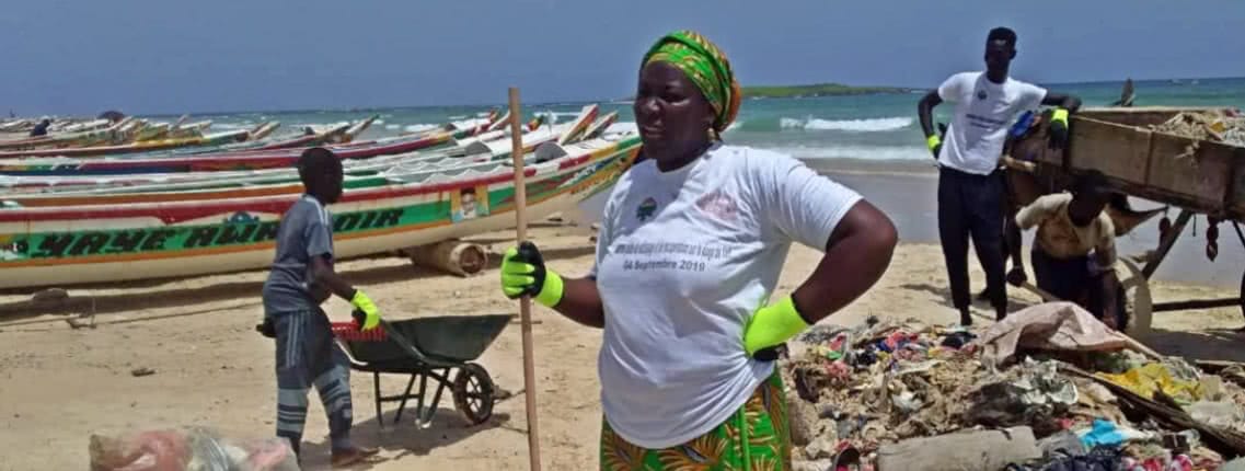 Members of Bokk Diom and local fisherfolk cleaning a beach together in Dakar.