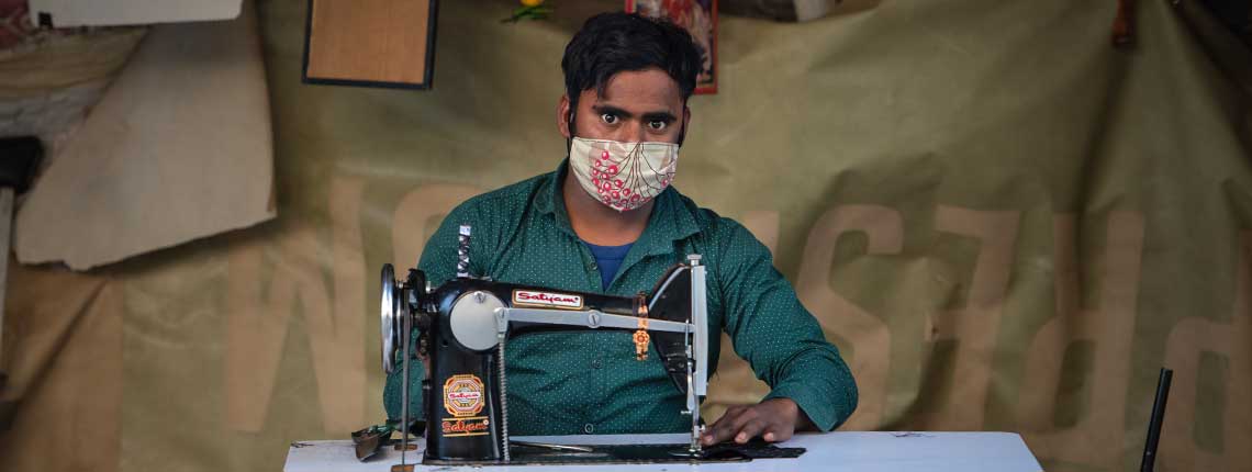 working in India with sewing machine making masks