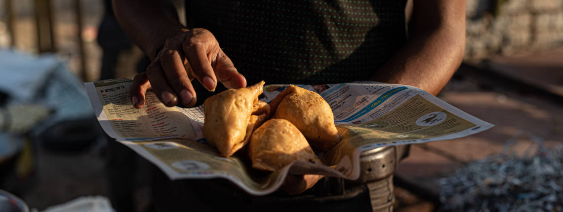 A vendor holds up freshly made samosas, a fried street food in Delhi.