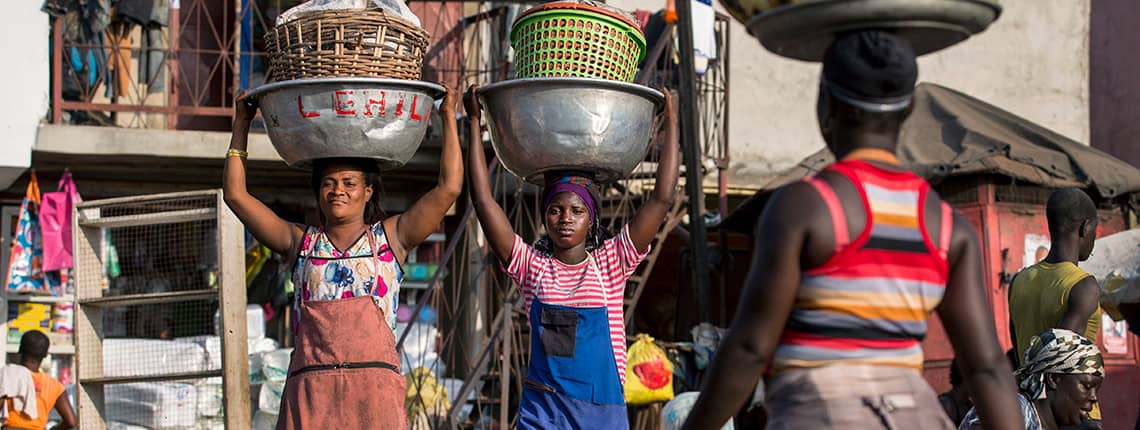 Kayayei carry a load full of goods on their heads at Agbogbloshie Market in Accra, Ghana