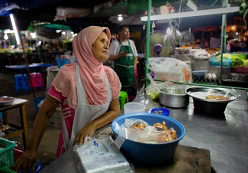Mujer vendiendo comida en mercado de Bangkok