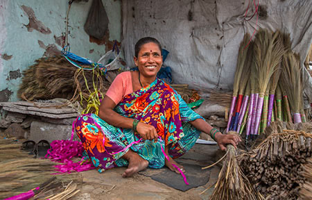 Shakuntala Rameshman makes brooms at her roadside stand on a busy street in Ahmedabad.
